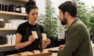 Asesora compara paquetes neutros de semillas con un cliente adulto en un grow shop